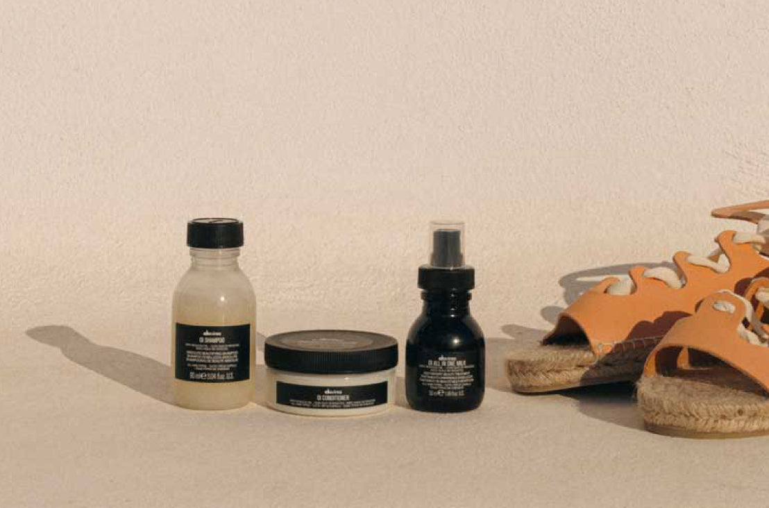 Davines mini OI Shampoo, conditioner, and all in one milk next to a pair of orange sandals